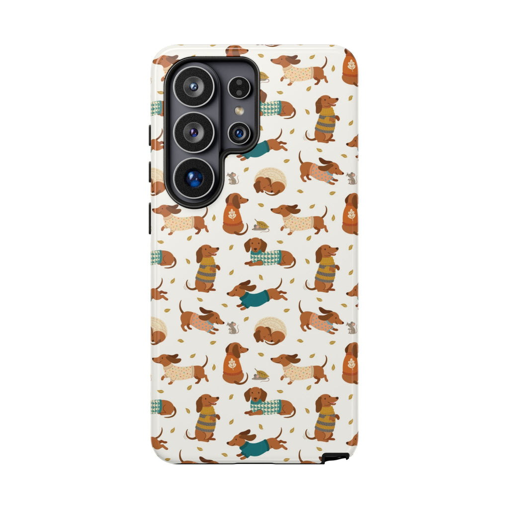 Sweater Weather Samsung Galaxy phone case featuring adorable dachshund dogs wearing colorful patterned sweaters on a warm ivory background.