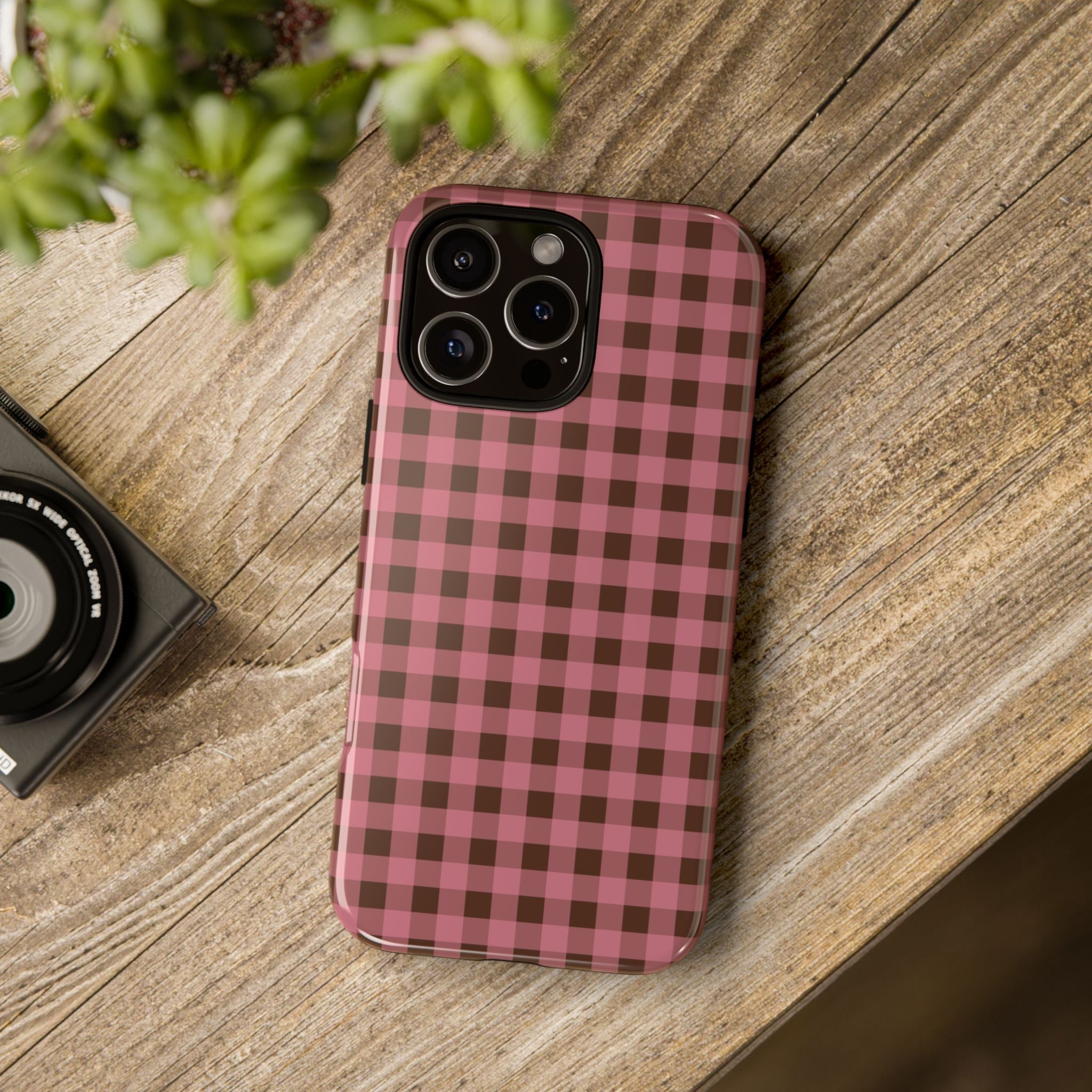 Phone case with pink and brown checkered pattern on a wooden surface