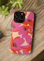 Floral phone case on a wooden surface with a camera and plant in the background