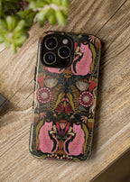 Phone case with floral and cat design on a wooden surface next to a camera