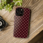 Phone case with polka dot pattern on a wooden surface next to a camera