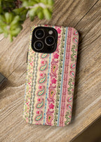 Phone case with paisley pattern on a wooden surface next to a camera and plant