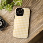 Phone case with checkered pattern on a wooden surface next to a camera