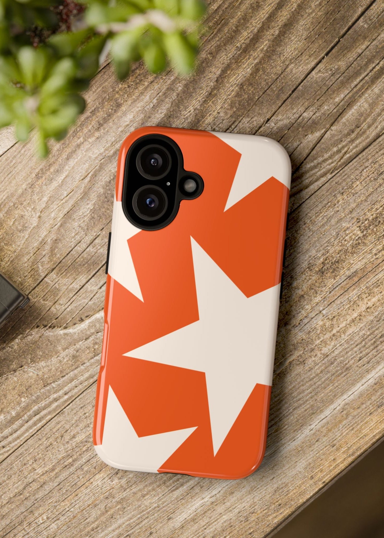 Phone case with star pattern on a wooden surface next to a camera