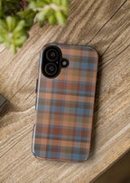Phone case with plaid pattern on a wooden surface next to a camera