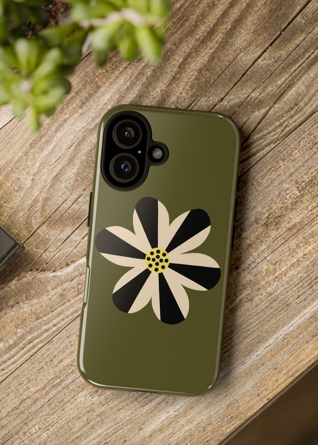 Phone case with a floral design on a wooden surface next to a camera