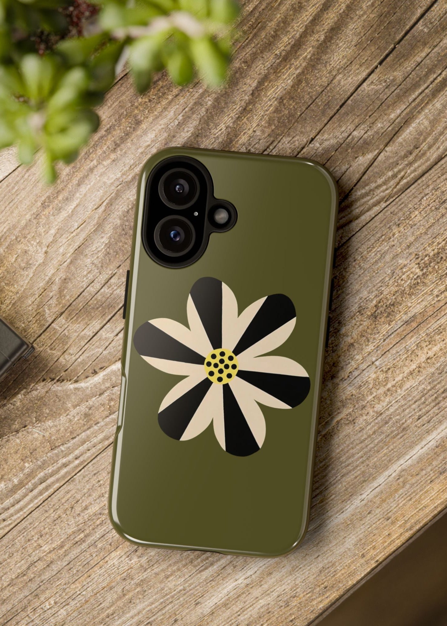 Phone case with a floral design on a wooden surface next to a camera