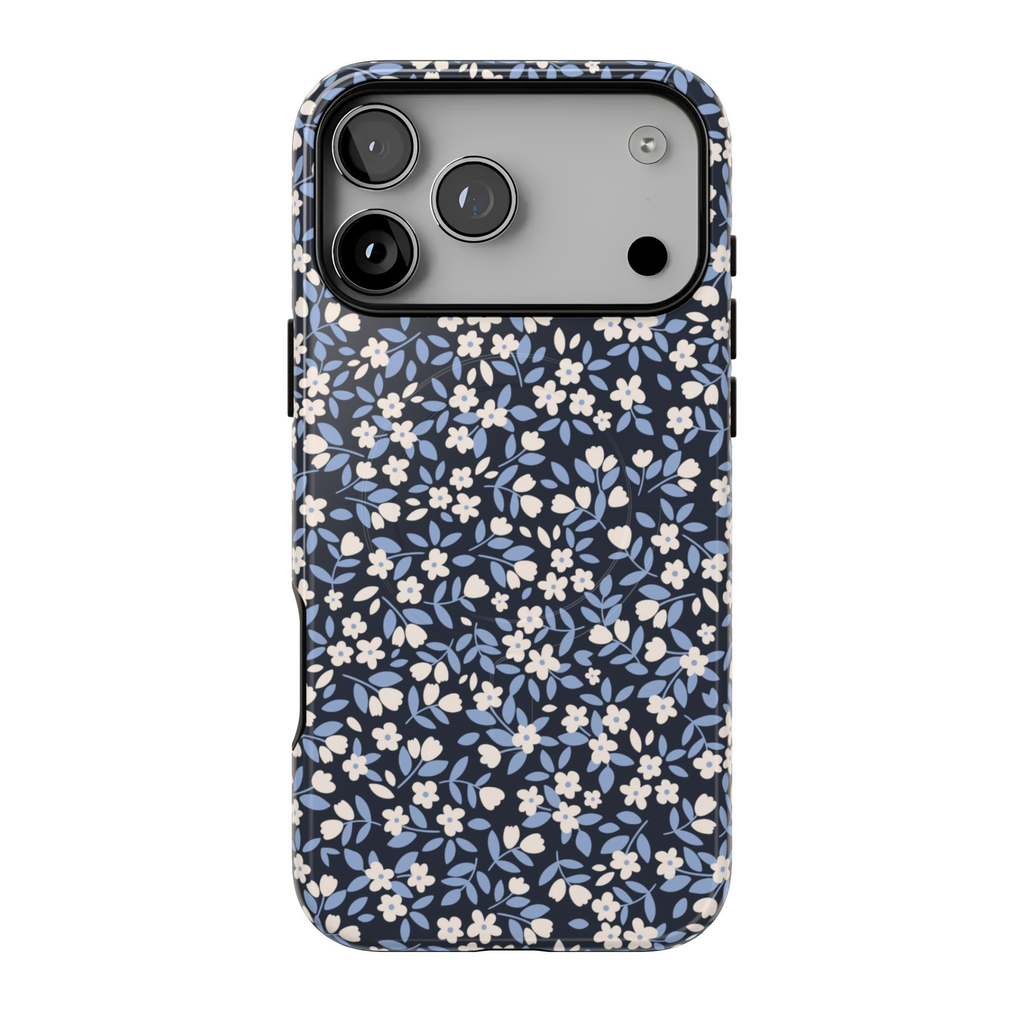 Ditsy Darling MagSafe case featuring tiny ivory flowers, dusty blue leaves, and delicate botanical details on a dark navy blue background.