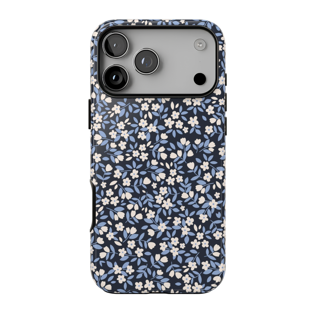 Ditsy Darling protective iPhone case featuring tiny ivory flowers, dusty blue leaves, and delicate botanical details on a dark navy blue background.